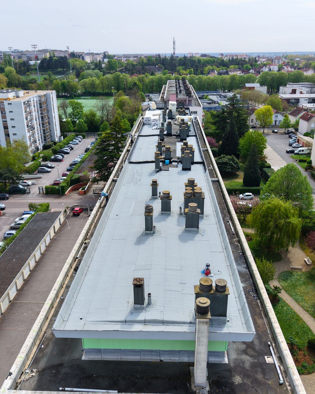 Pose de membrane d'étanchéité synthétique (TPO/PVC) Blanc sur toiture-terrasse inaccessible de bâtiment collectif – finition lisse, soudure à l'air chaud.